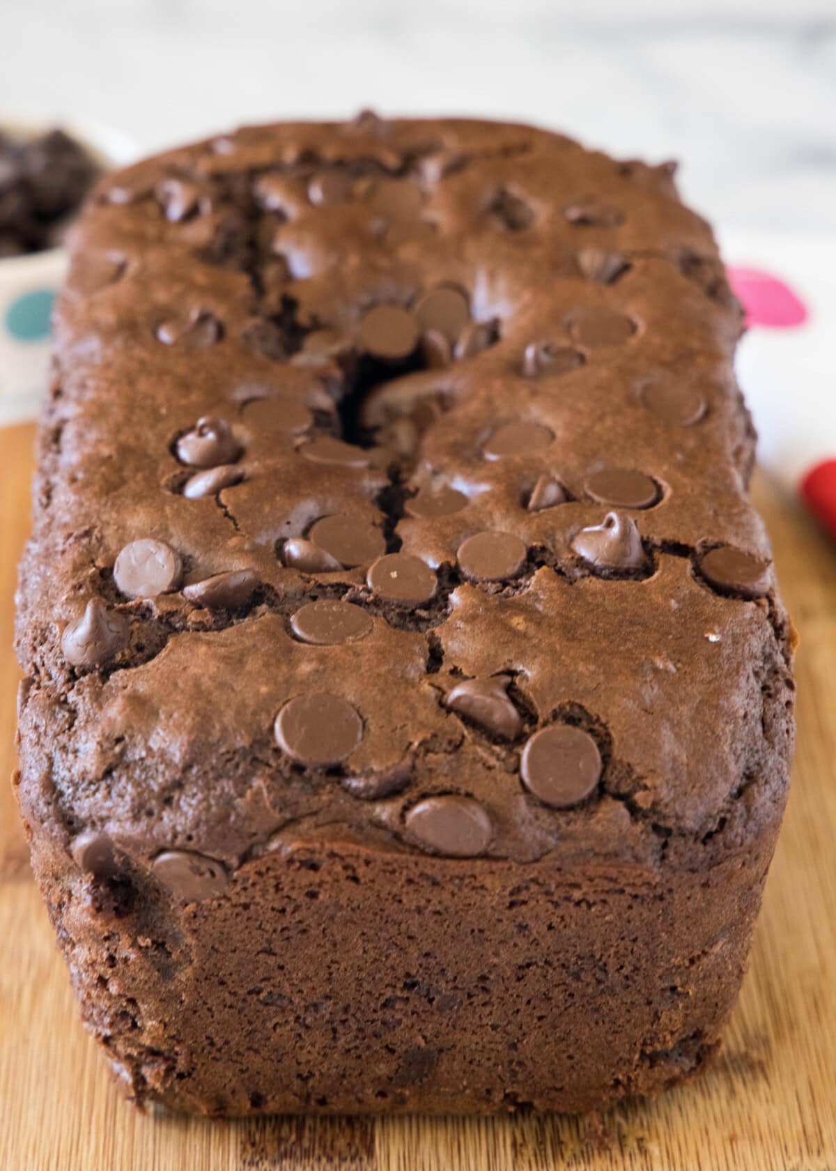 This quick chocolate bread is moist, chocolatey, and ready for the oven in 10 minutes! Loaded with chocolate chips, it's an easy sweet treat. Baked chocolate bread on a wooden cutting board.