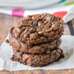 A stack of three brownie mix cookies on a piece of parchment paper.