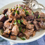 Slow cooker steak bites in a serving bowl with a large fork.