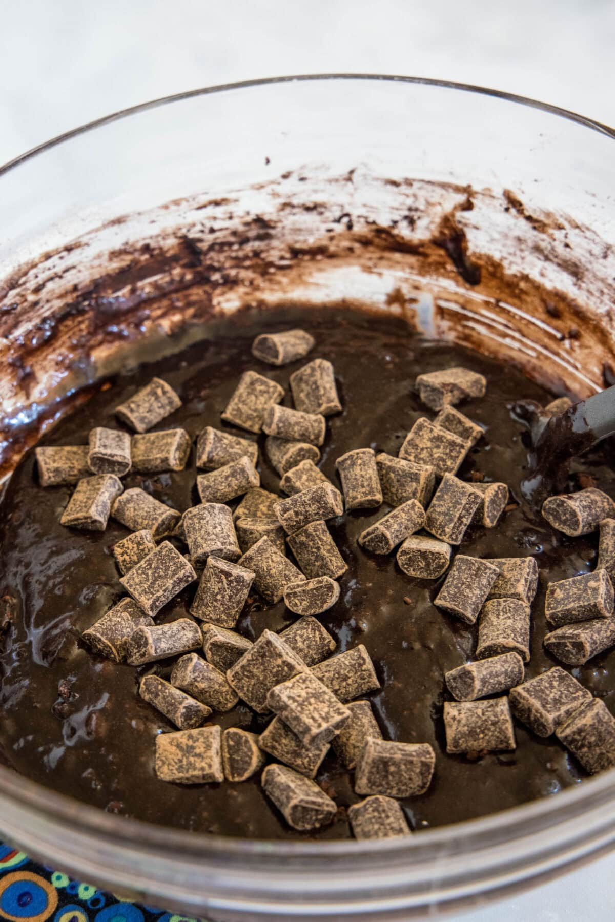 Make thick and chewy, fudgy double chocolate brownies with cocoa powder and chocolate chunks, for loads of melty chocolate in every bite! Chocolate chunks added to brownie batter in a glass mixing bowl.