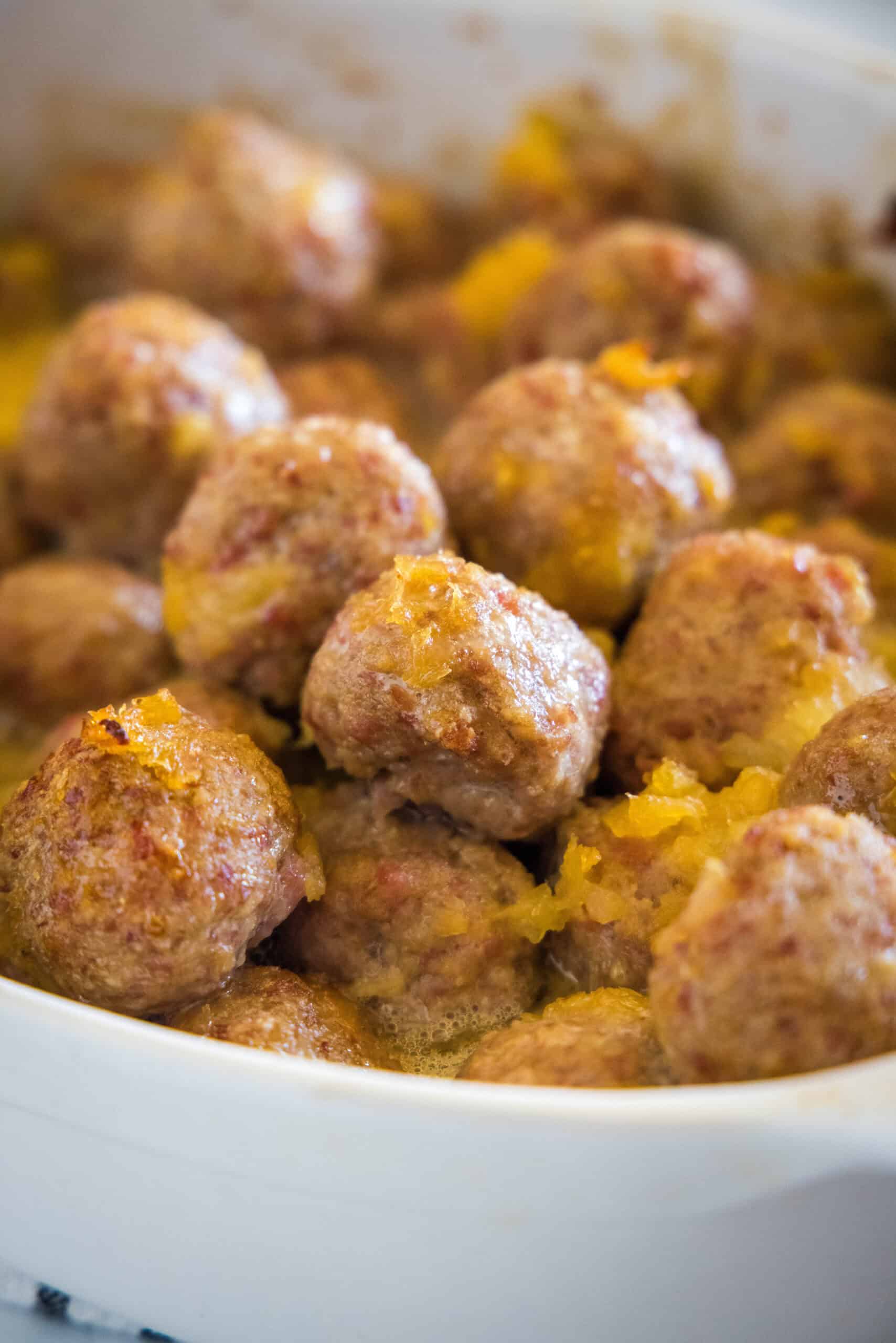 Close up of baked ham balls with pineapple sauce in a baking dish.