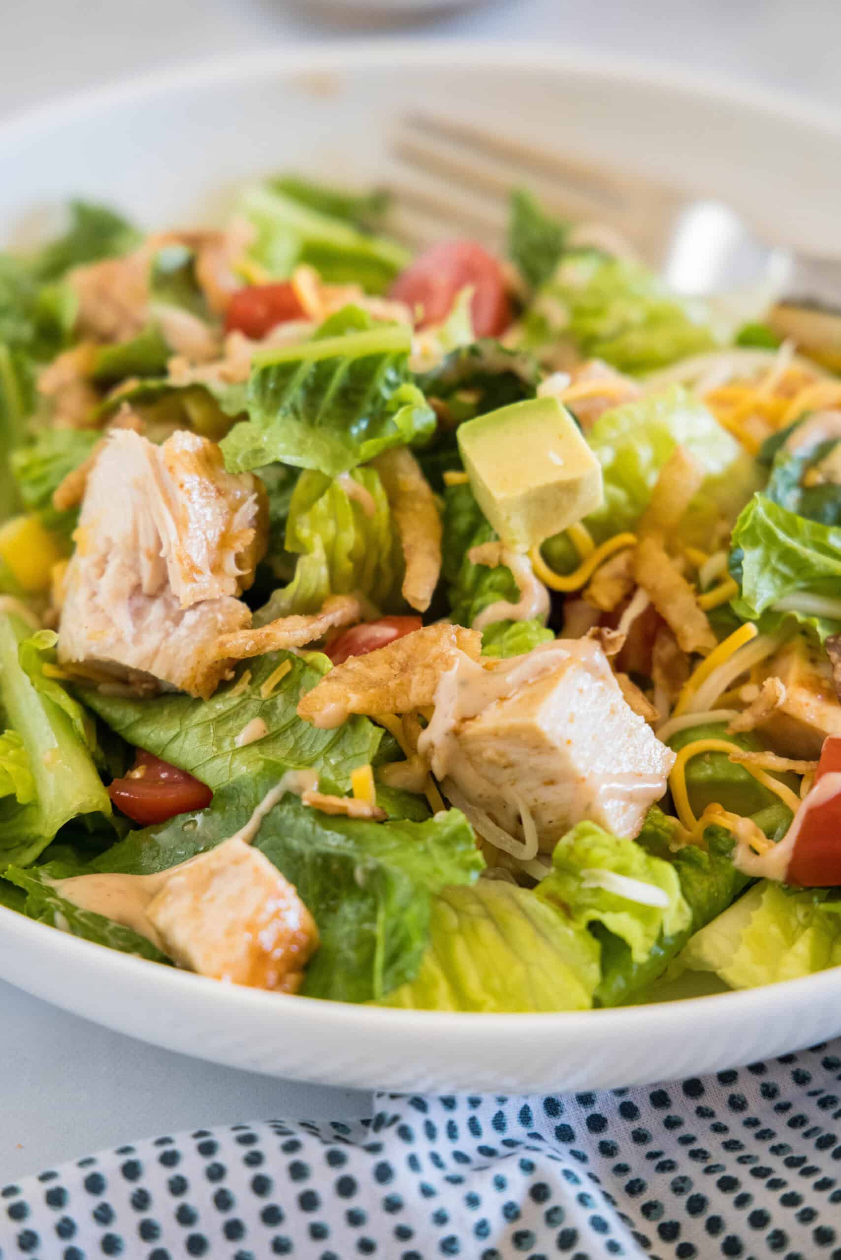 Close up of BBQ chicken salad in a white bowl with a fork.