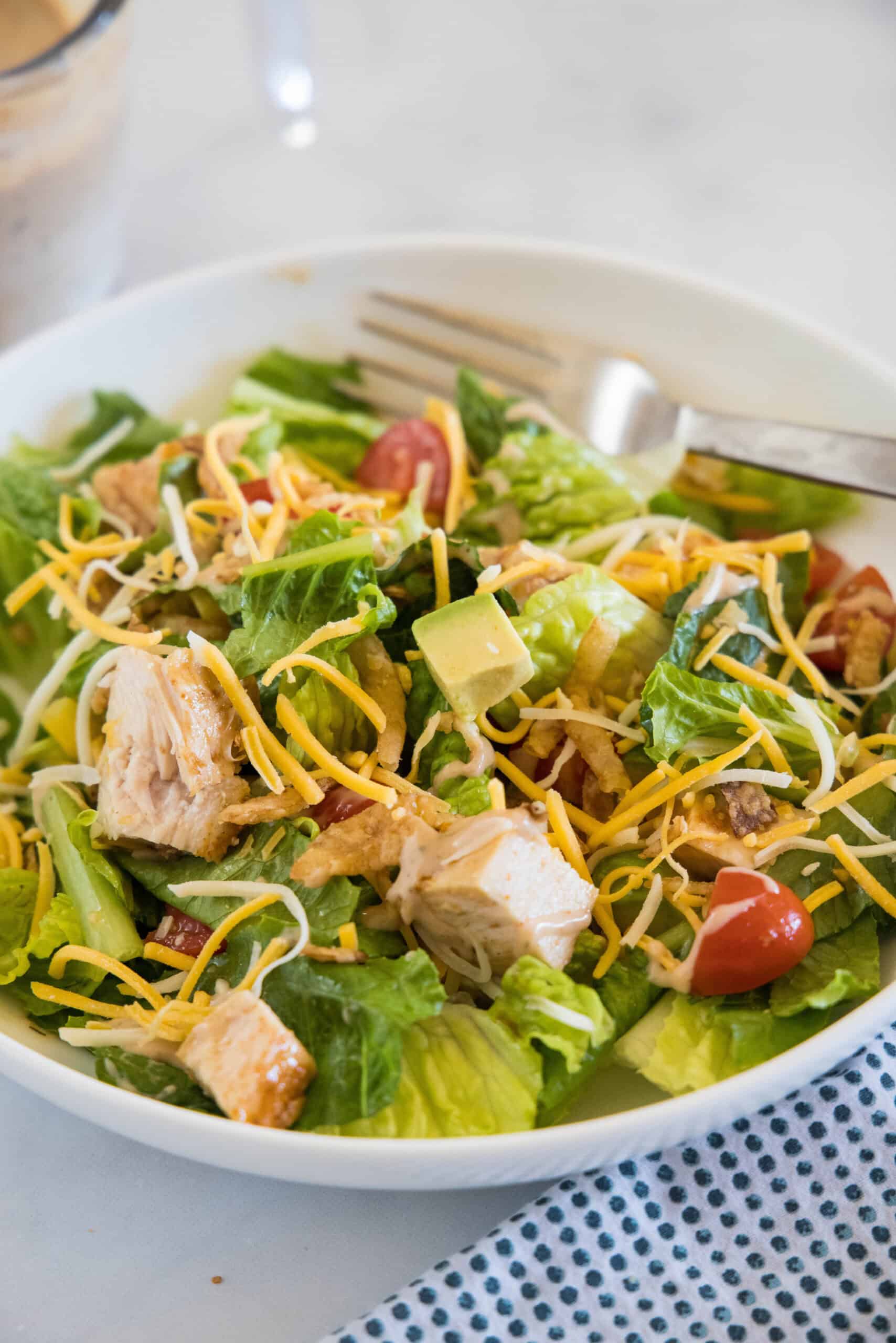 BBQ chicken salad in a white bowl with a fork.