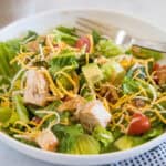 BBQ chicken salad in a white bowl with a fork.