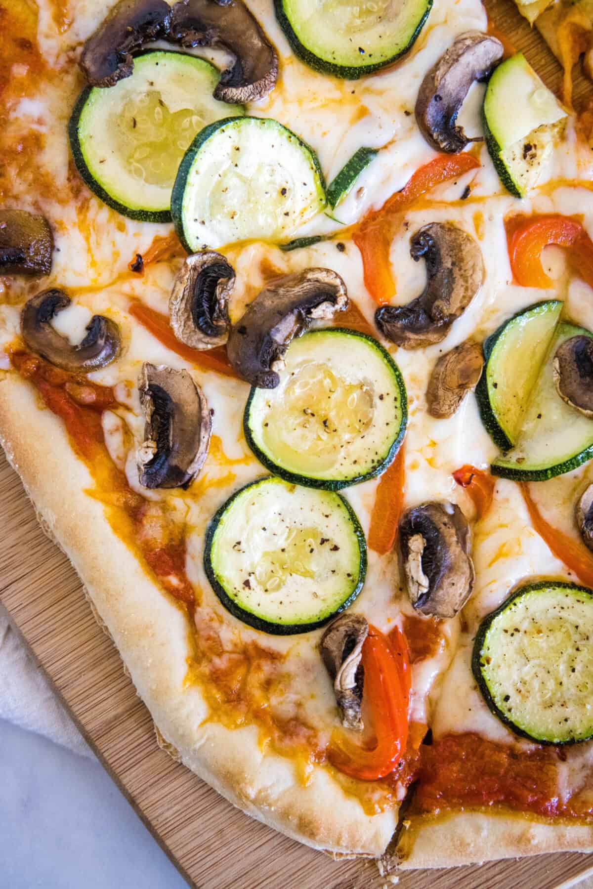 Roasted Veggie Pizza | Dinners, Dishes, and Desserts looking down on sliced roasted veggie pizza on a cutting board