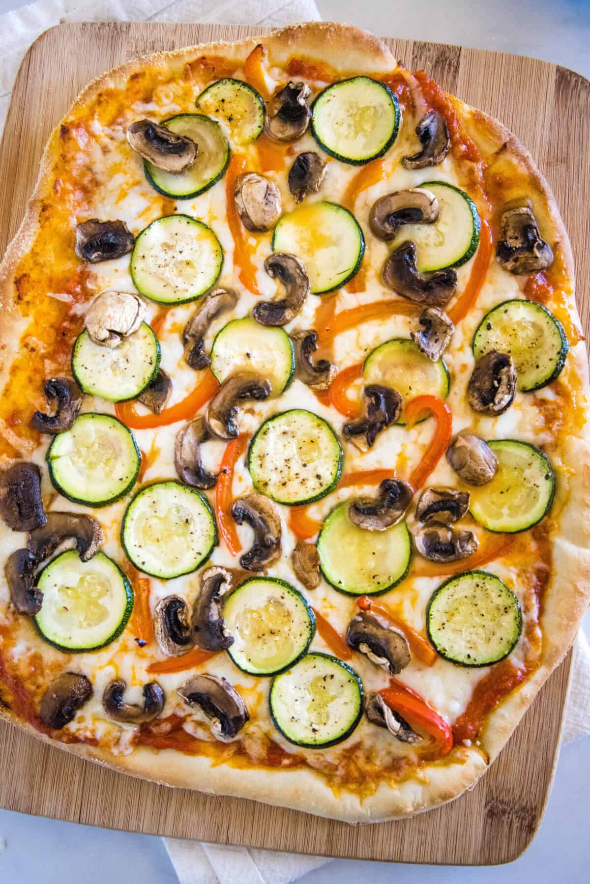 baked roasted vegetable pizza on cutting board