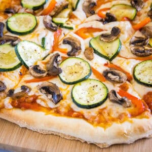 close up sliced roasted vegetable pizza on cutting board