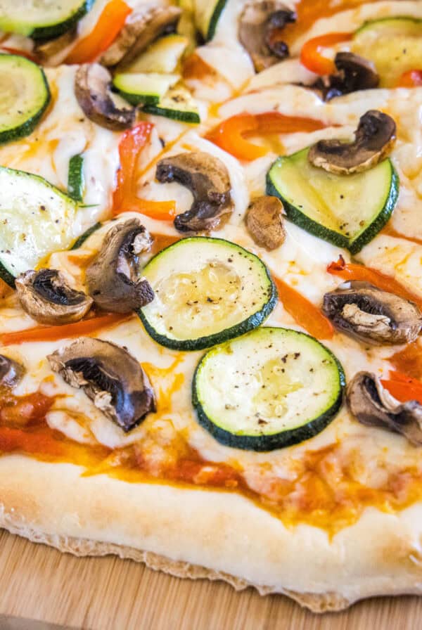 close up sliced roasted vegetable pizza on cutting board