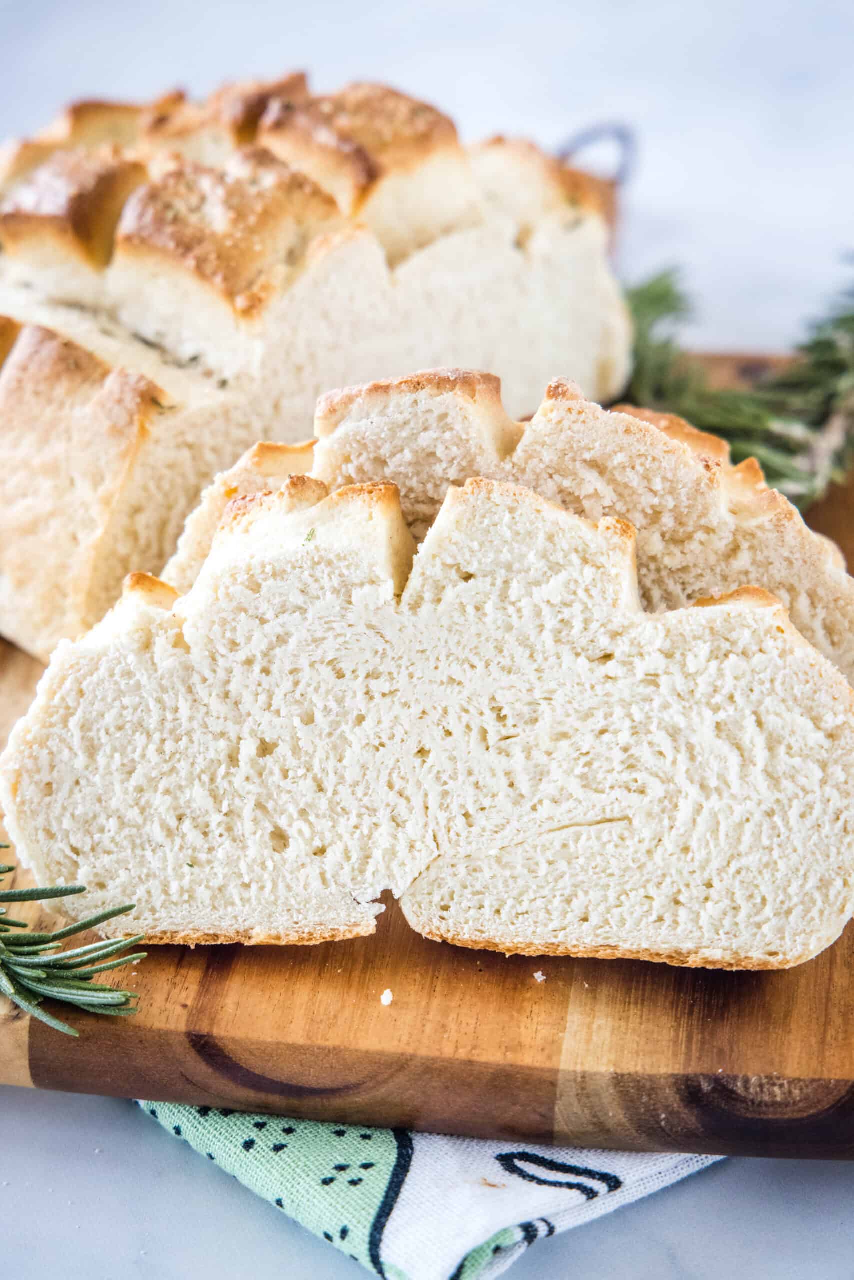 Slices of Amish bread on a wooden cutting board with the rest of the loaf in the background.