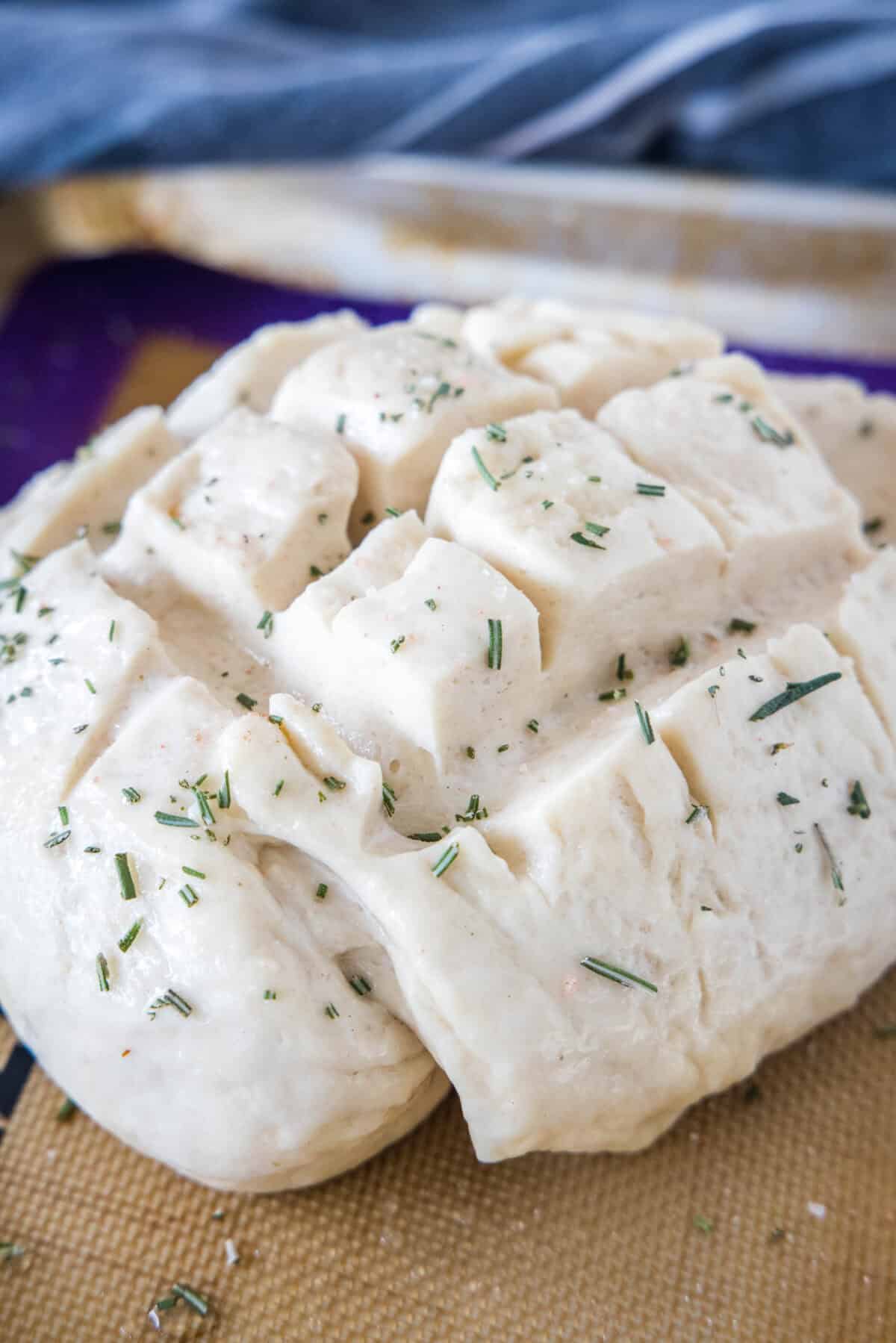 Amish bread dough sprinkled with herbs before baking.