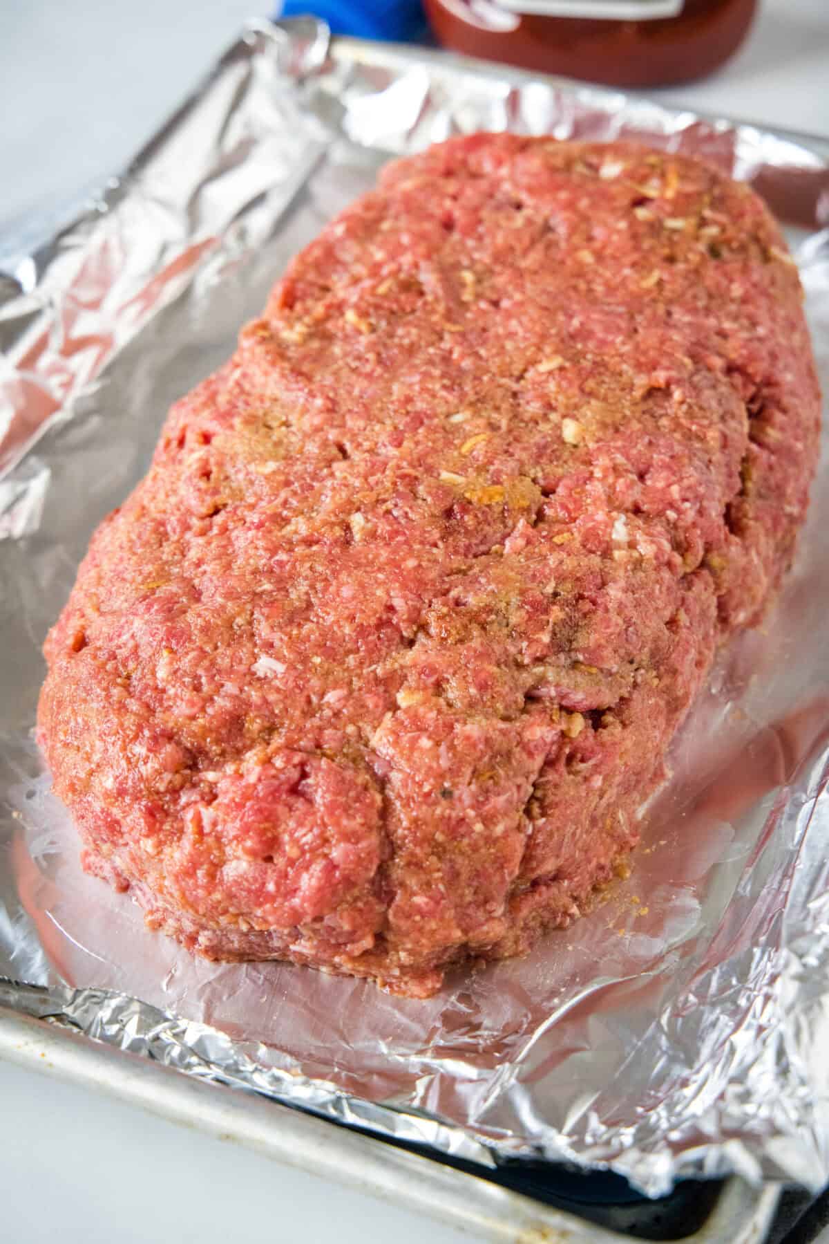 Shaped onion soup meatloaf on a foil-lined baking sheet.
