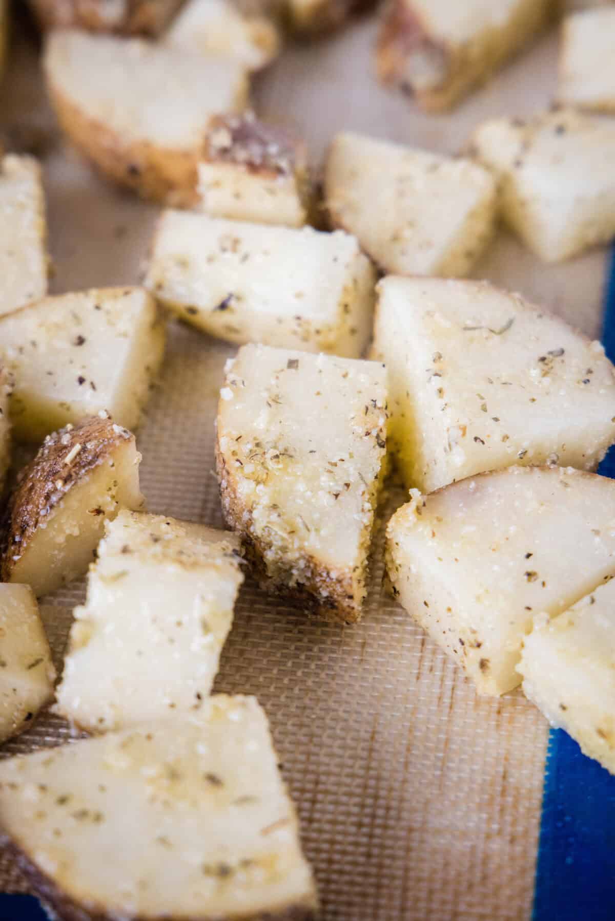 Close up of seasoned potatoes on a baking sheet.