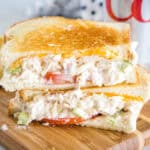 Two halves of a tuna melt stacked on top of one another on a wooden platter.