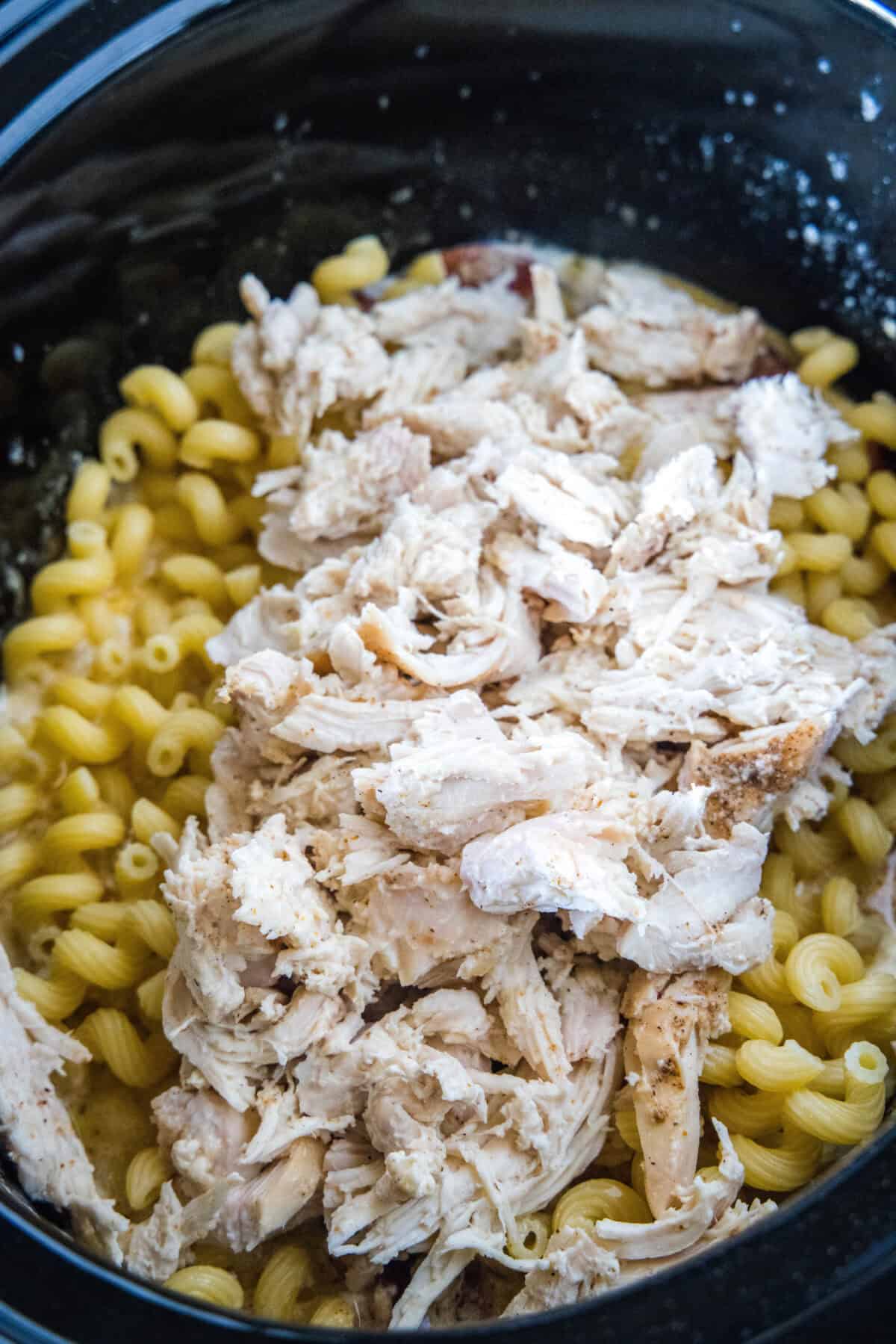 This creamy crockpot Cajun chicken pasta is easy to make in the slow cooker with spicy sausage and a rich, cheesy sauce. Just add pasta! Shredded chicken and pasta added to Cajun sauce in a slow cooker.