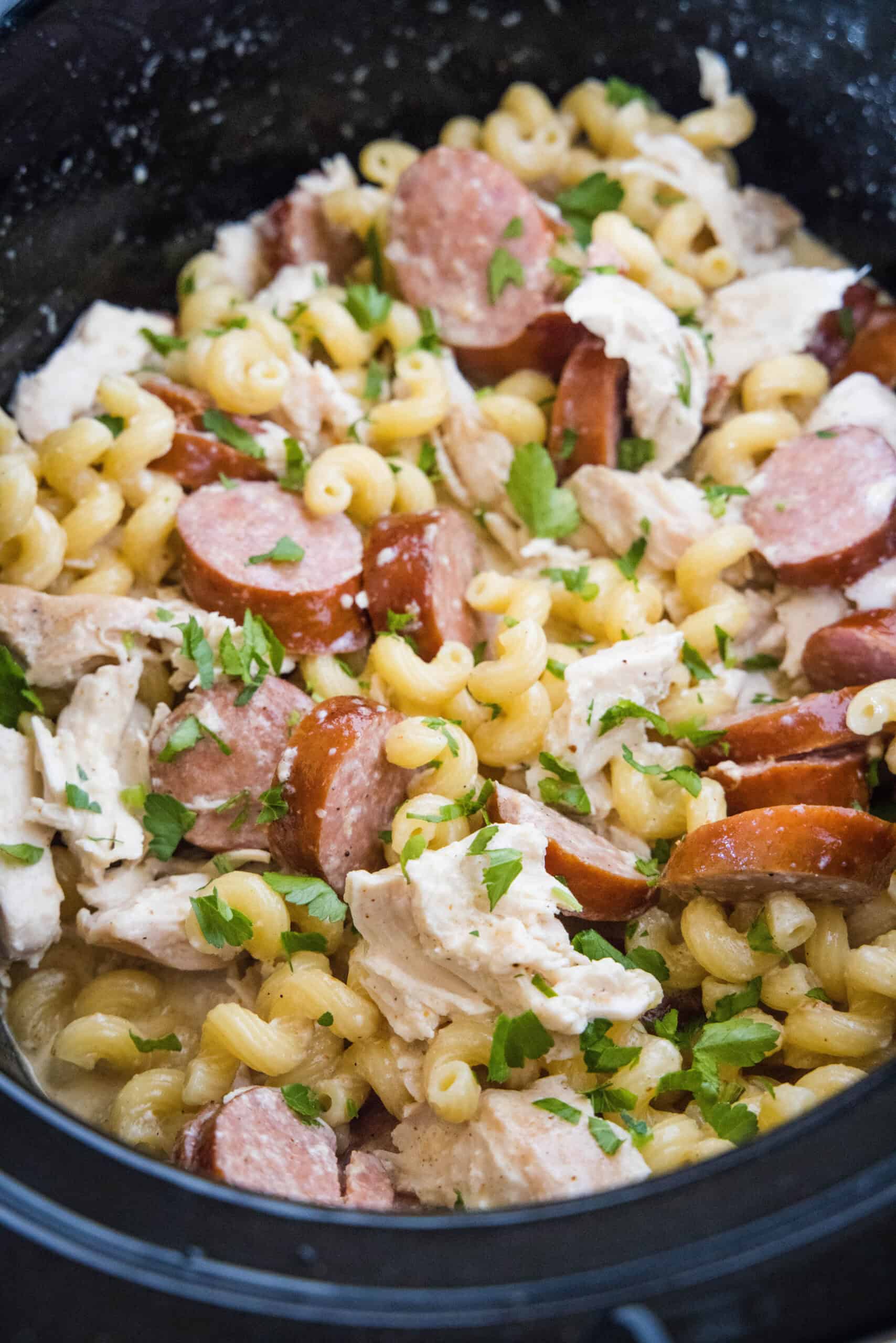 This creamy crockpot Cajun chicken pasta is easy to make in the slow cooker with spicy sausage and a rich, cheesy sauce. Just add pasta! Overhead view of crockpot Cajun chicken pasta inside the slow cooker.