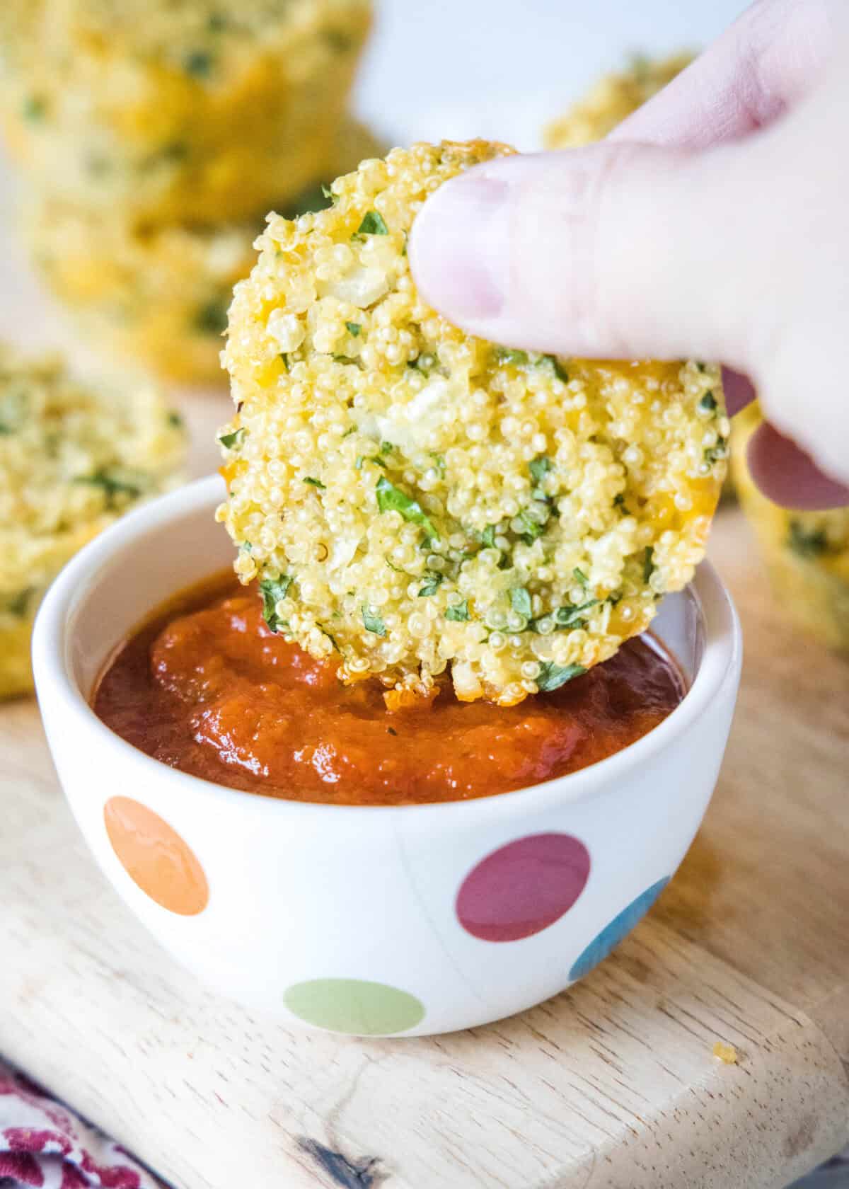 dipping quinoa bite into marinara sauce