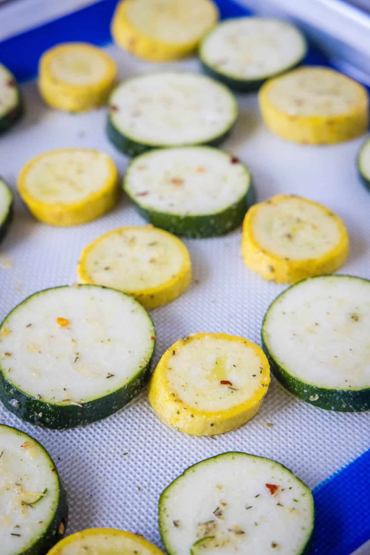 Make perfectly tender-crisp roasted zucchini and squash in the oven. It's an easy vegetable side dish that's ready in 20 minutes! Seasoned squash and zucchini slices arranged in a single layer on a lined baking sheet.