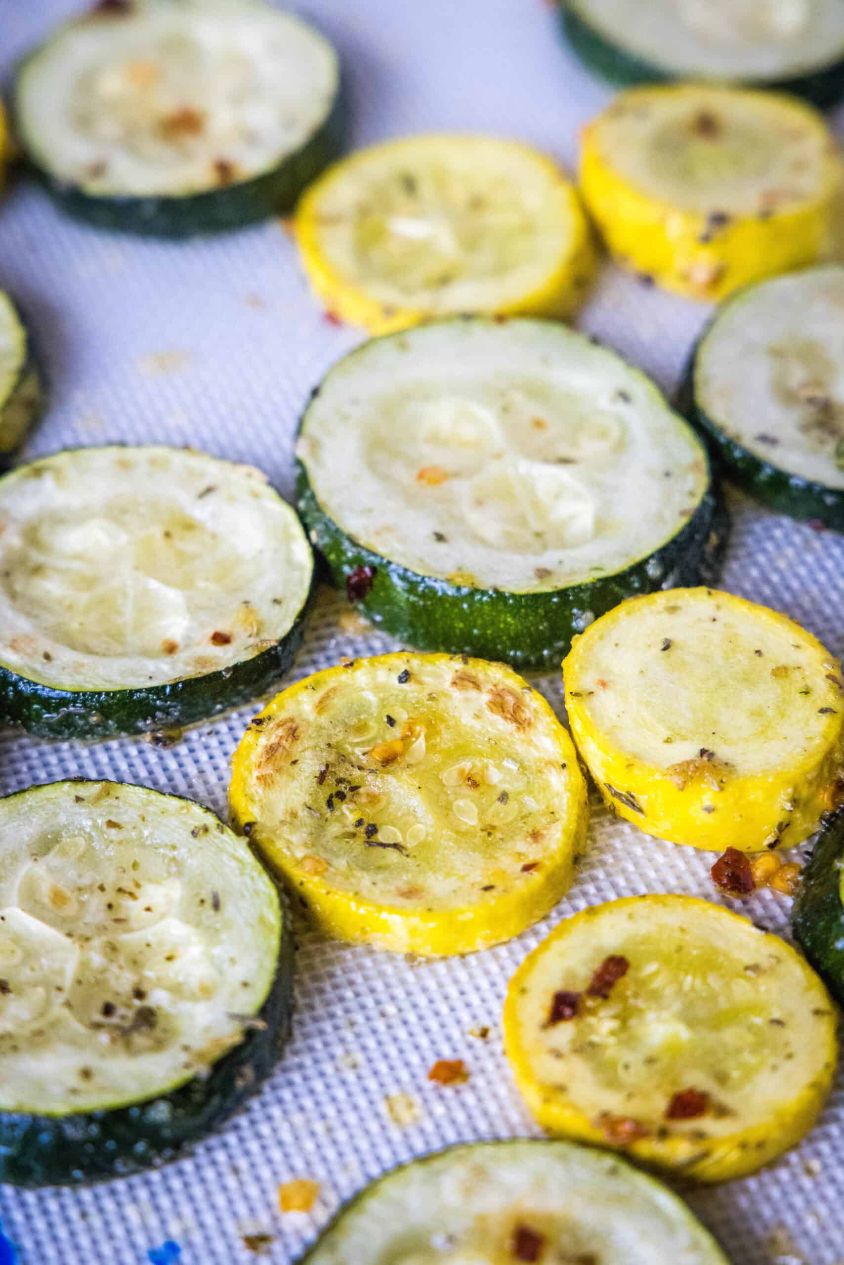 Make perfectly tender-crisp roasted zucchini and squash in the oven. It's an easy vegetable side dish that's ready in 20 minutes! Roasted zucchini and squash slices on a lined baking sheet.