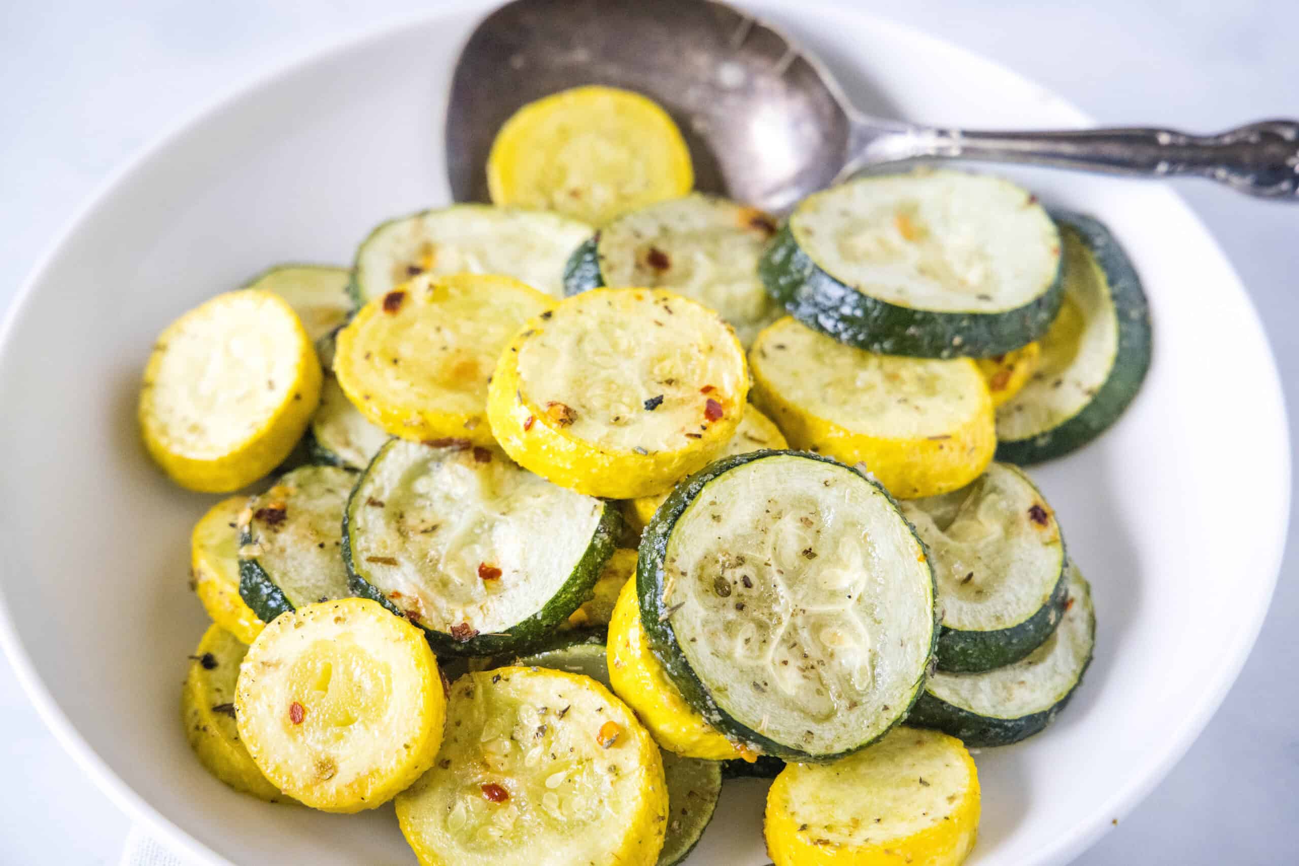 Make perfectly tender-crisp roasted zucchini and squash in the oven. It's an easy vegetable side dish that's ready in 20 minutes! Roasted zucchini and squash in a bowl with a serving spoon.