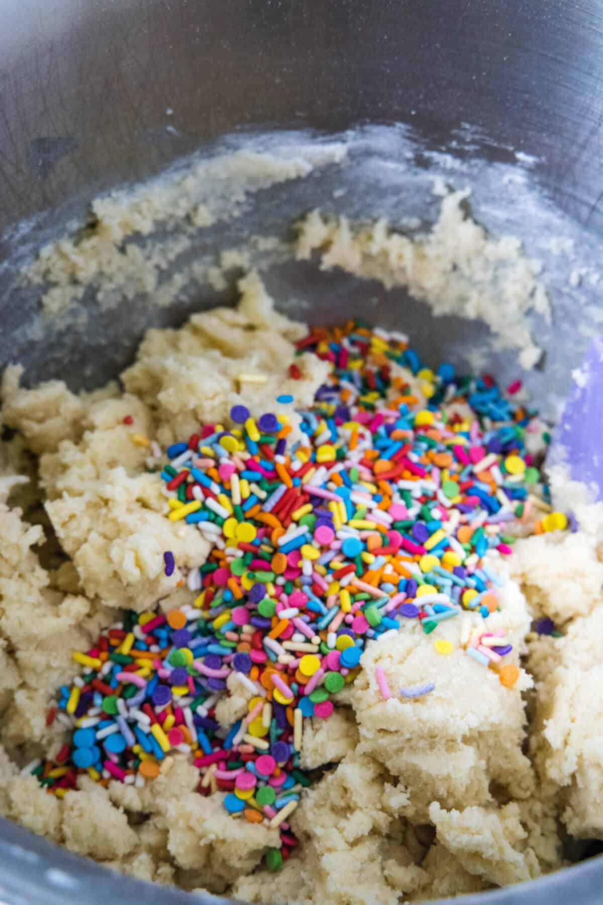 adding sprinkles to cookie dough in mixing bowl