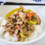 cropped close up pepper steak over rice on a white plate