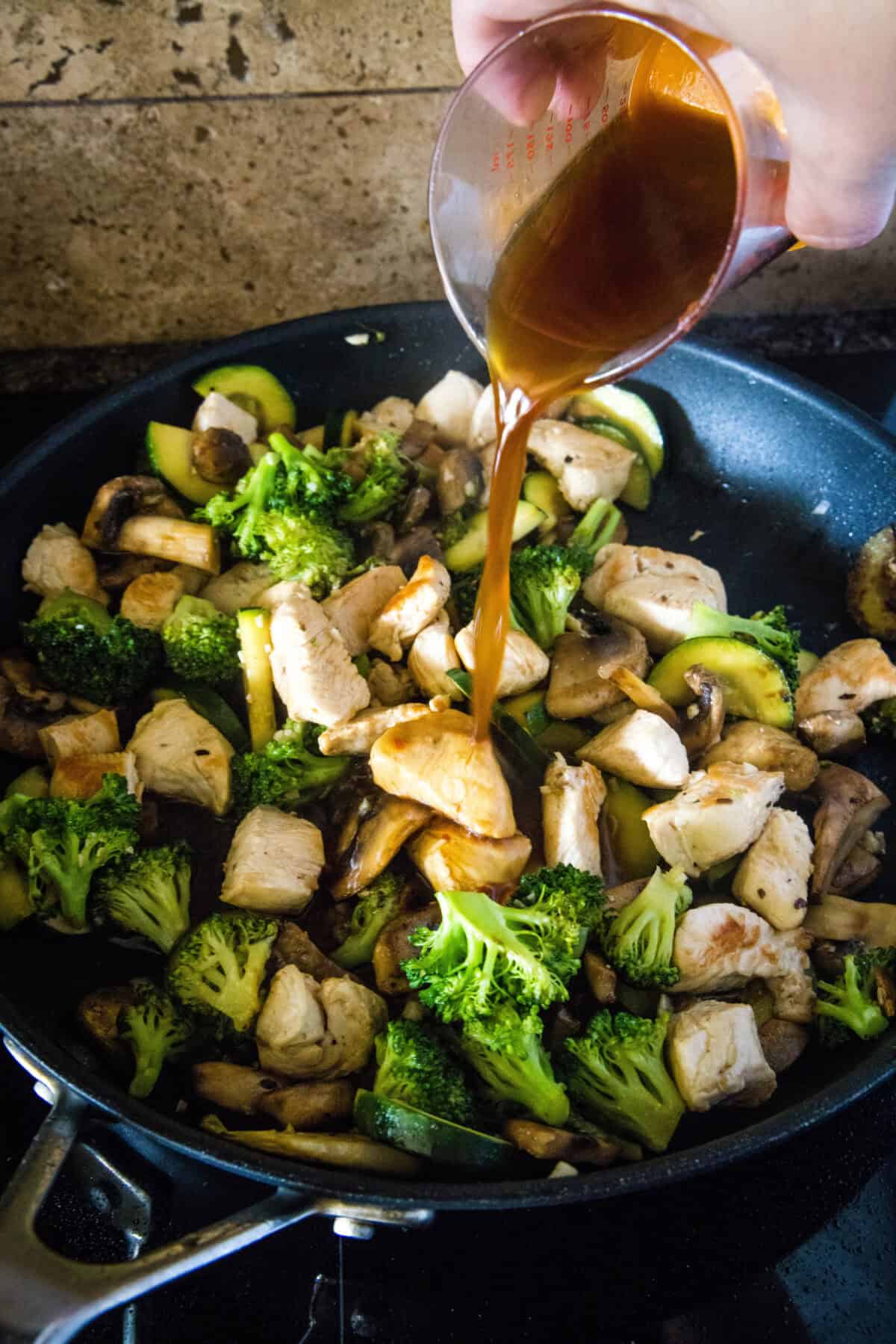 pouring stir fry sauce into skillet