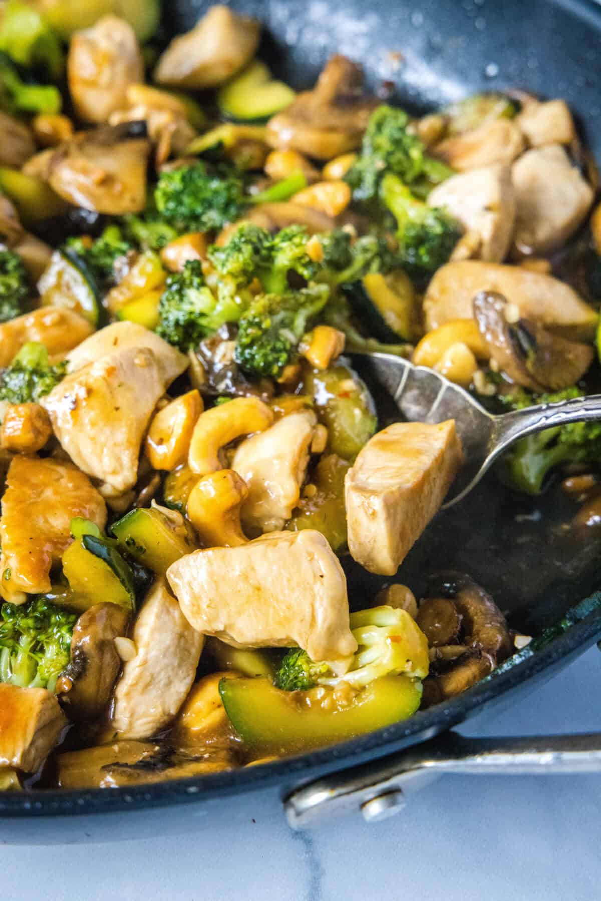 scooping chicken stir fry from skillet