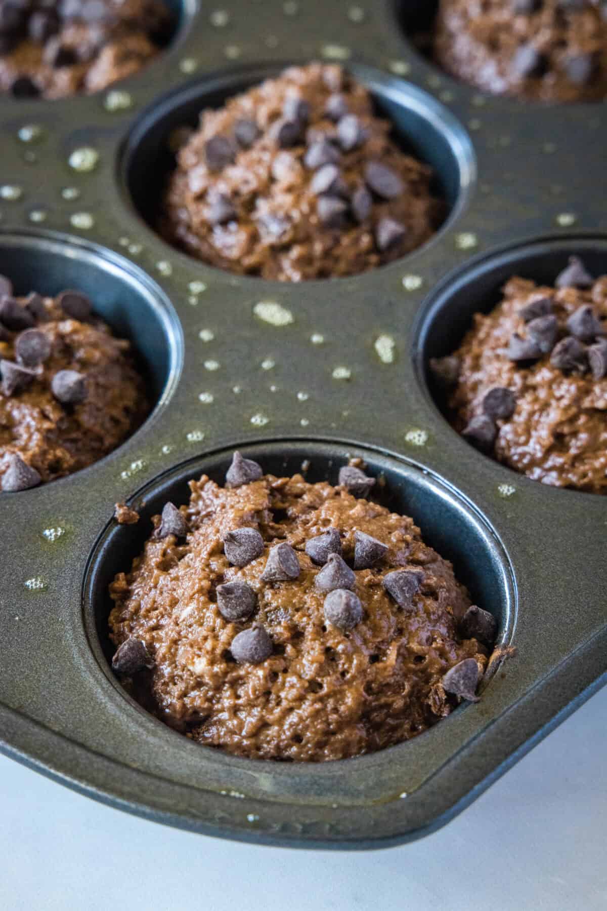 chocolate applesauce muffin batter in a muffin tin