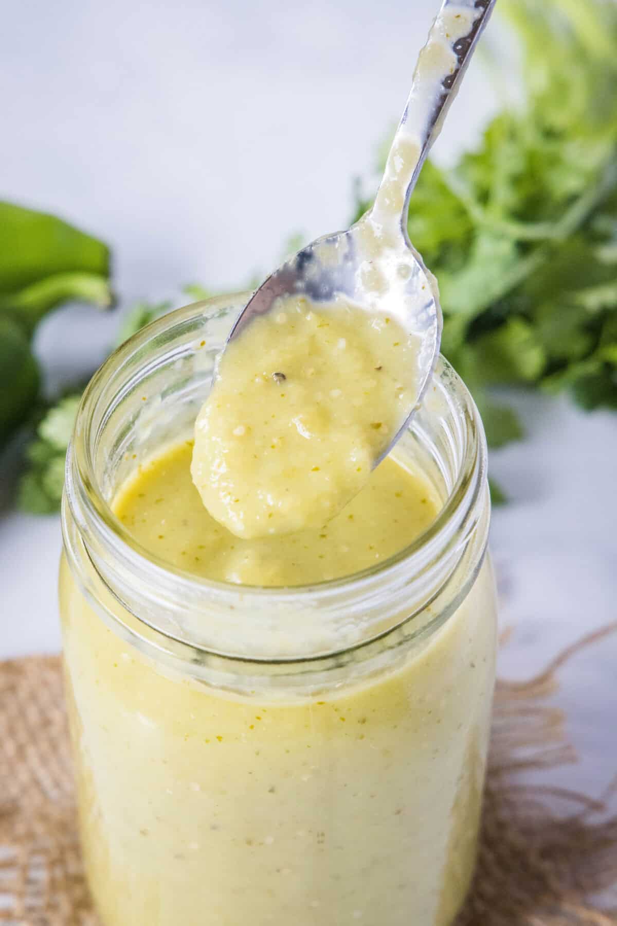spooning green chile enchilada sauce from a jar