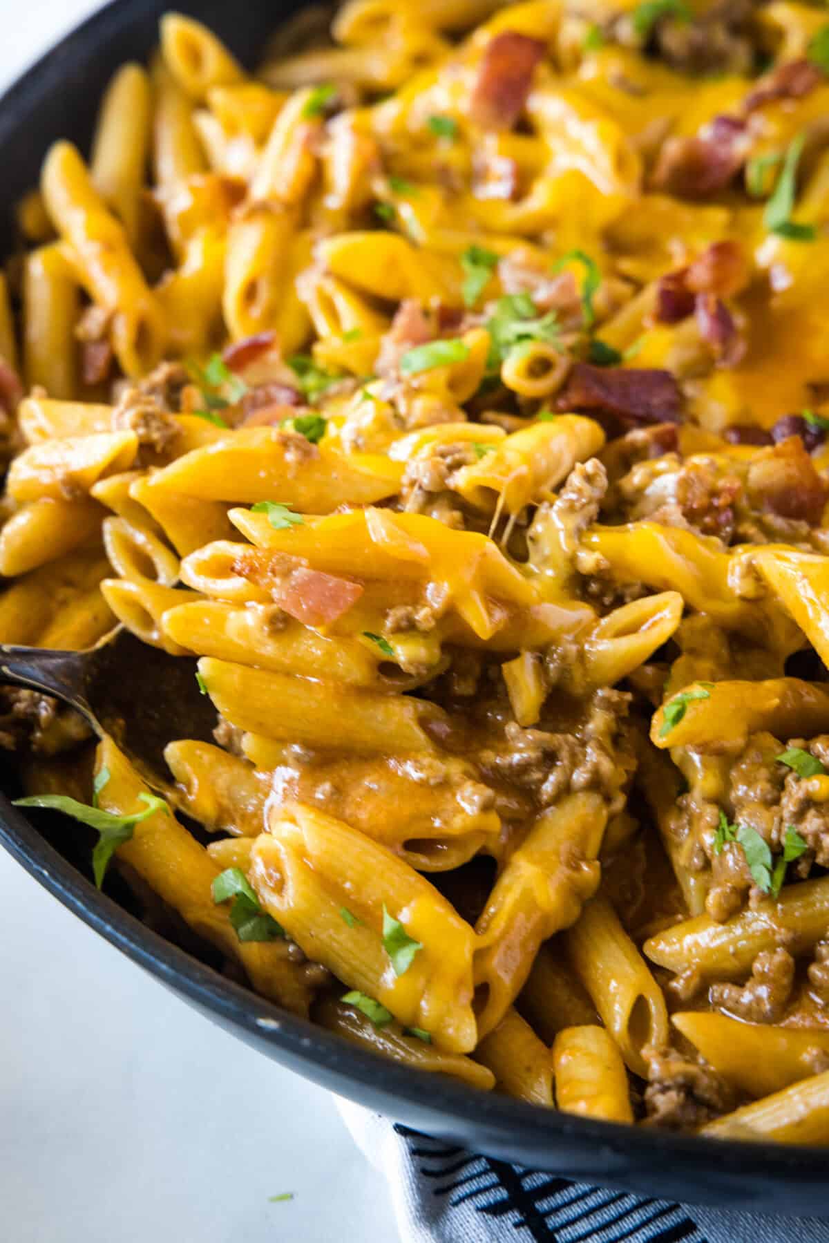 scooping bacon cheeseburger pasta from skillet
