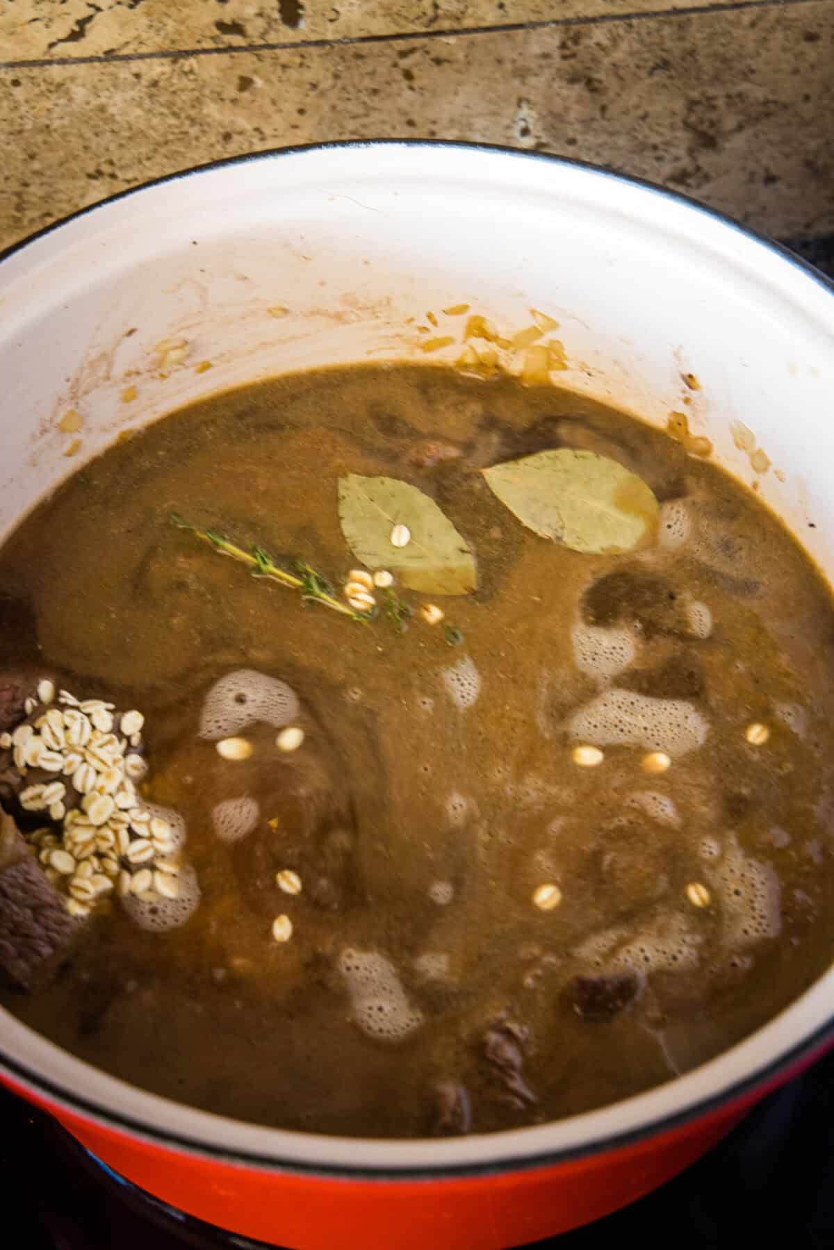 adding bay leaves and thyme to pot for soup