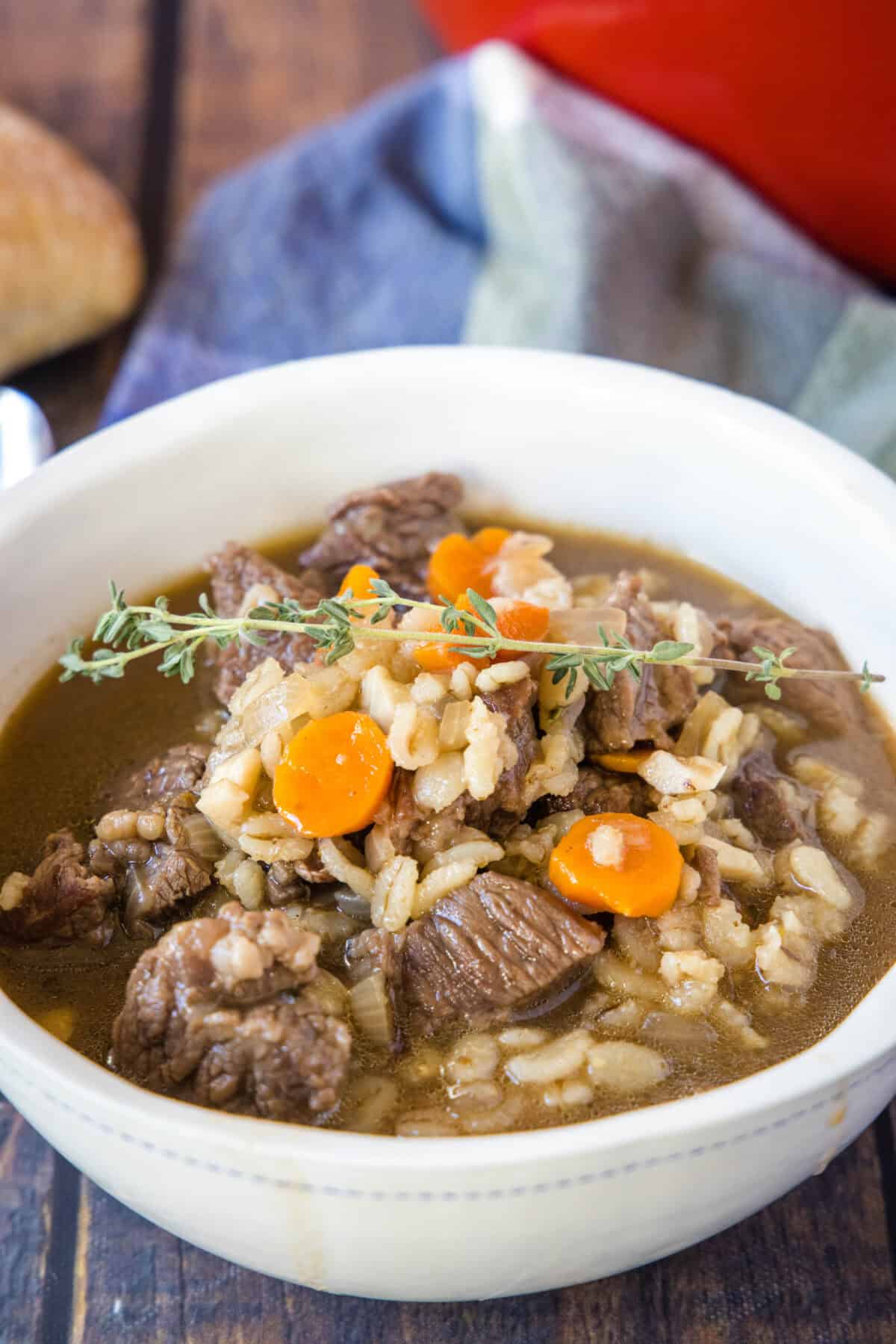 a white bowl full of beef barley soup