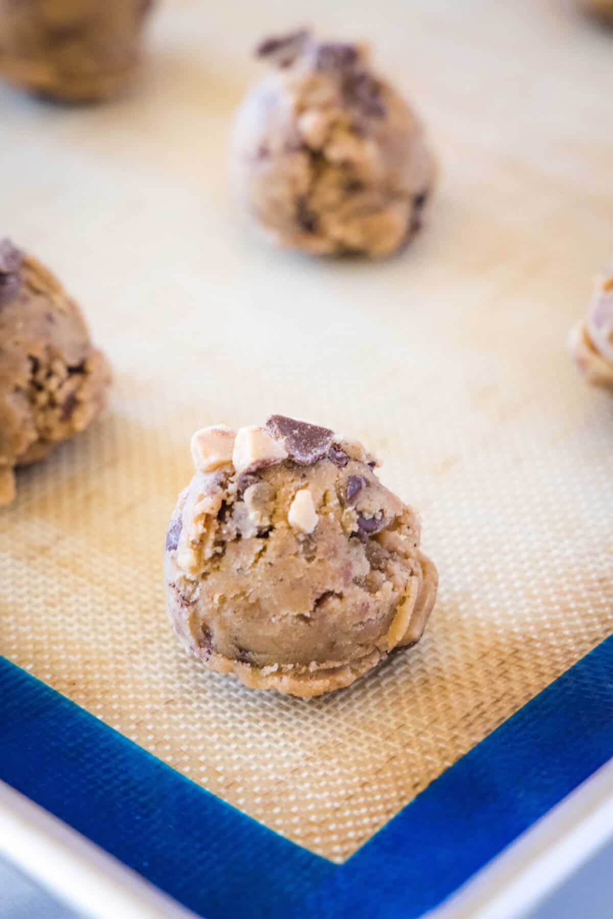 balls of chocolate chip toffee cookies on baking tray