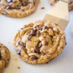 close up scooping chocolate chip toffee cookies from baking tray