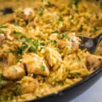 cropped close up scooping chicken and orzo from a skillet