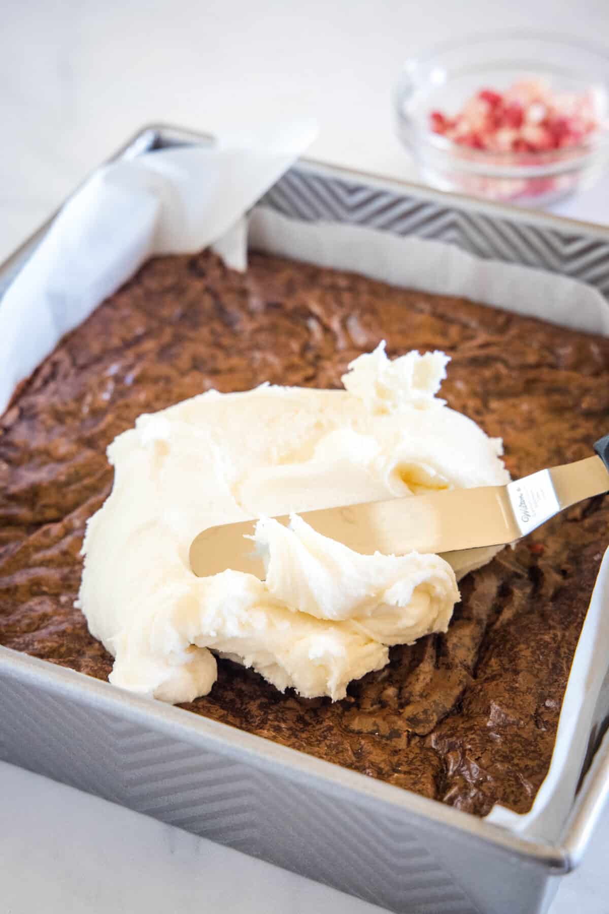 spreading frosting over brownies