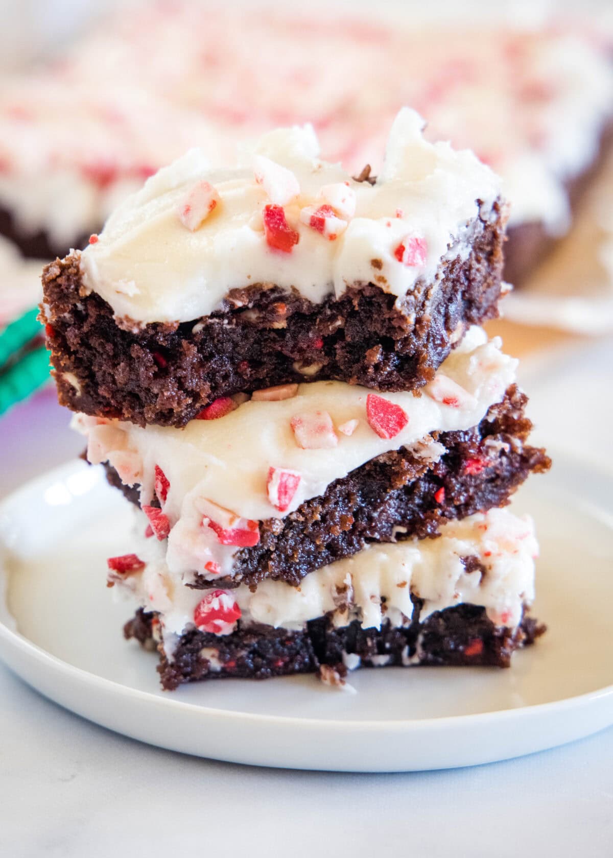 stacked close up of christmas brownies on a white plate with a bite taken out of one