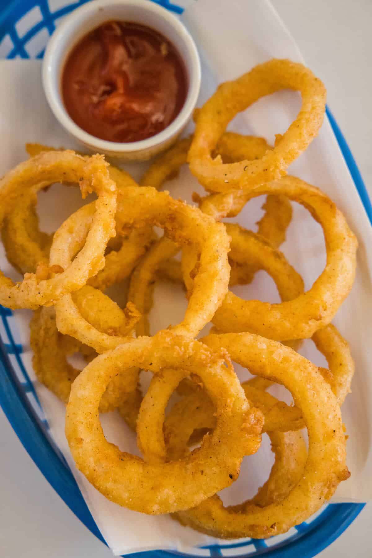 looking down on basket of onion rings and ketchup