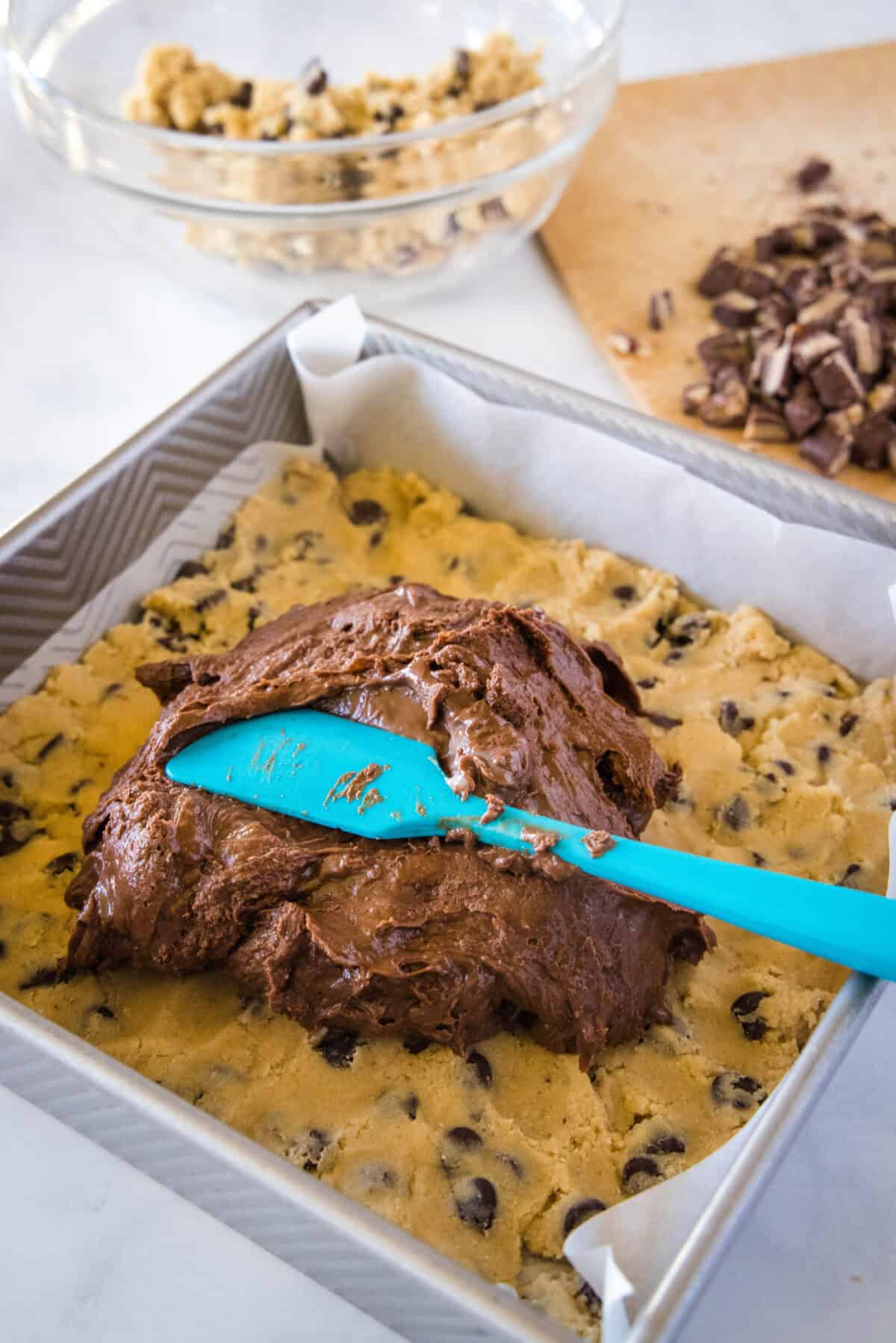 spreading chocolate fudge layer over cookie dough