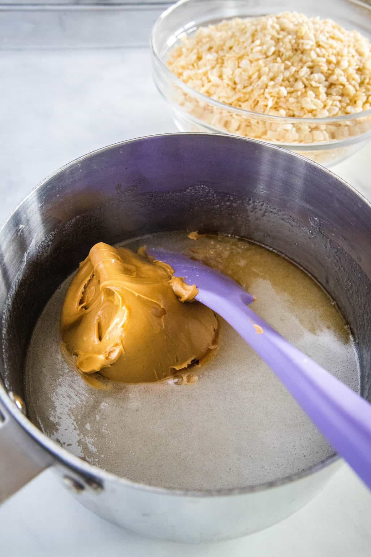 adding peanut butter to melted sugar mixture in saucepan