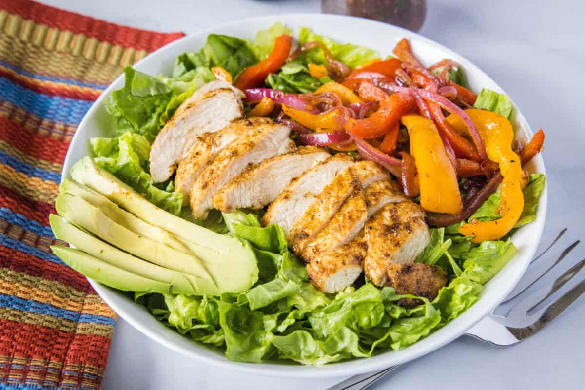 Chicken Fajita Salad – Juicy, seasoned chicken, sautéed peppers, and crisp romaine come together in this fresh, satisfying salad. Finished with a bold salsa-based dressing and creamy avocado, it delivers all the fajita flavor without the tortillas.