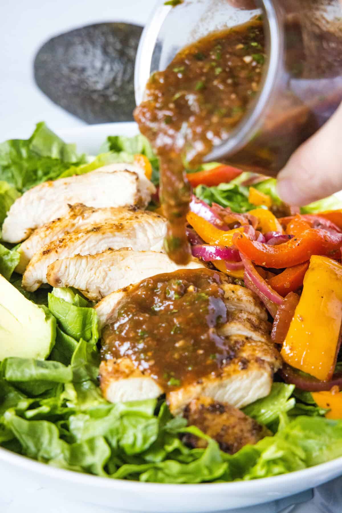 pouring salsa vinaigrette over chicken fajita salad
