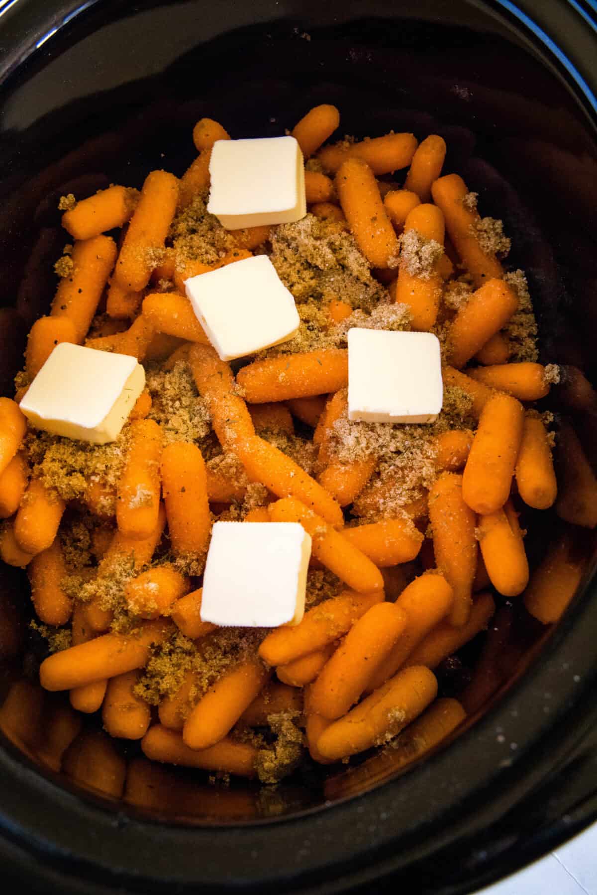 adding pats of butter to carrots in crockpot