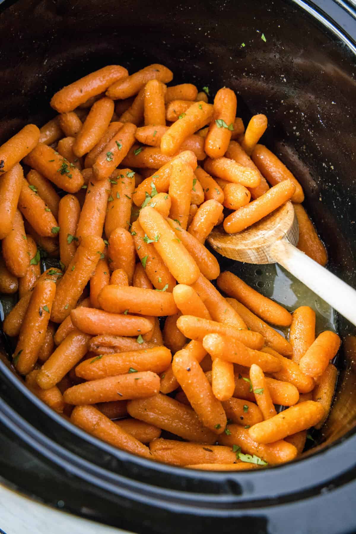 stirring roasted carrots in slow cooker