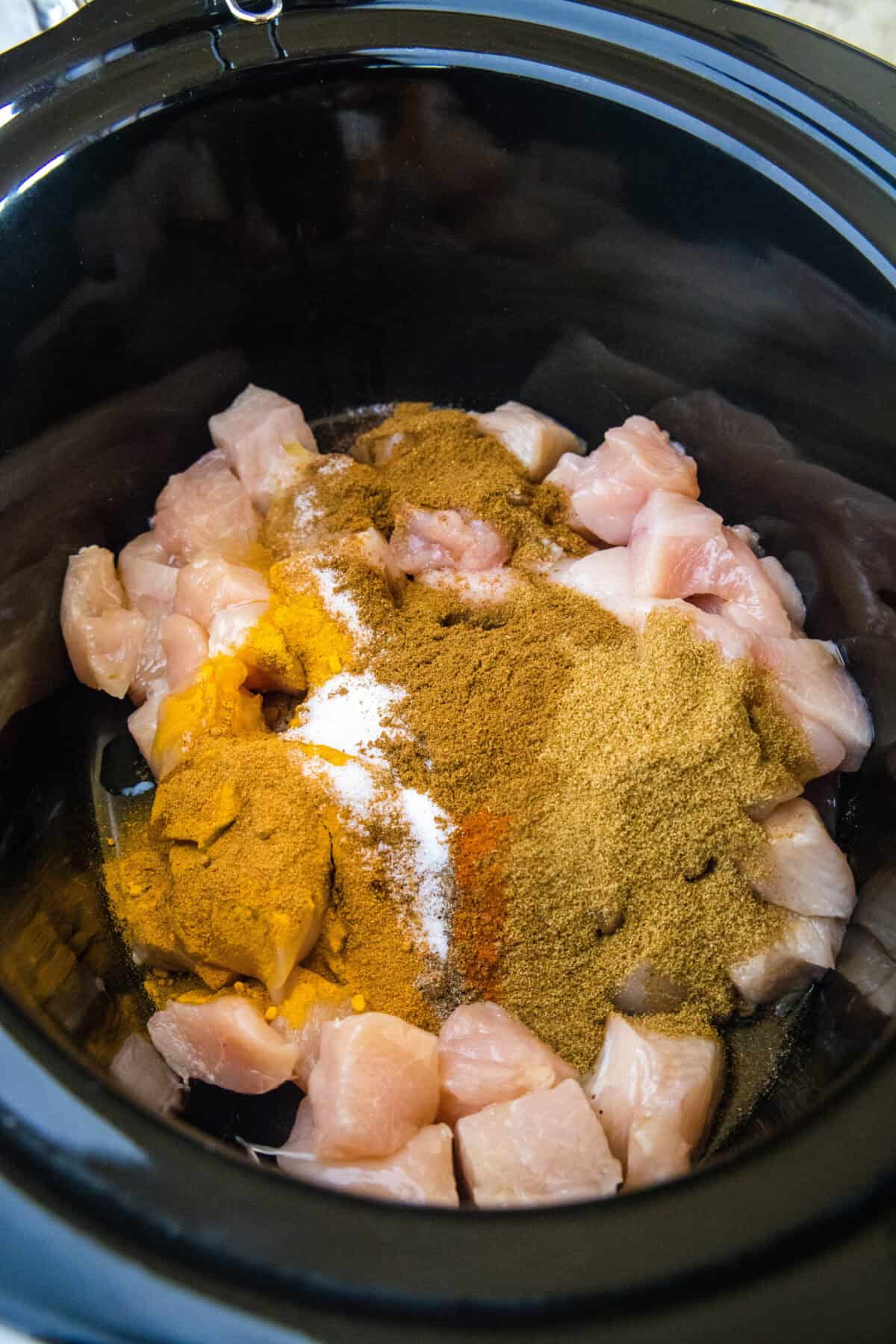 spices over diced chicken in crockpot