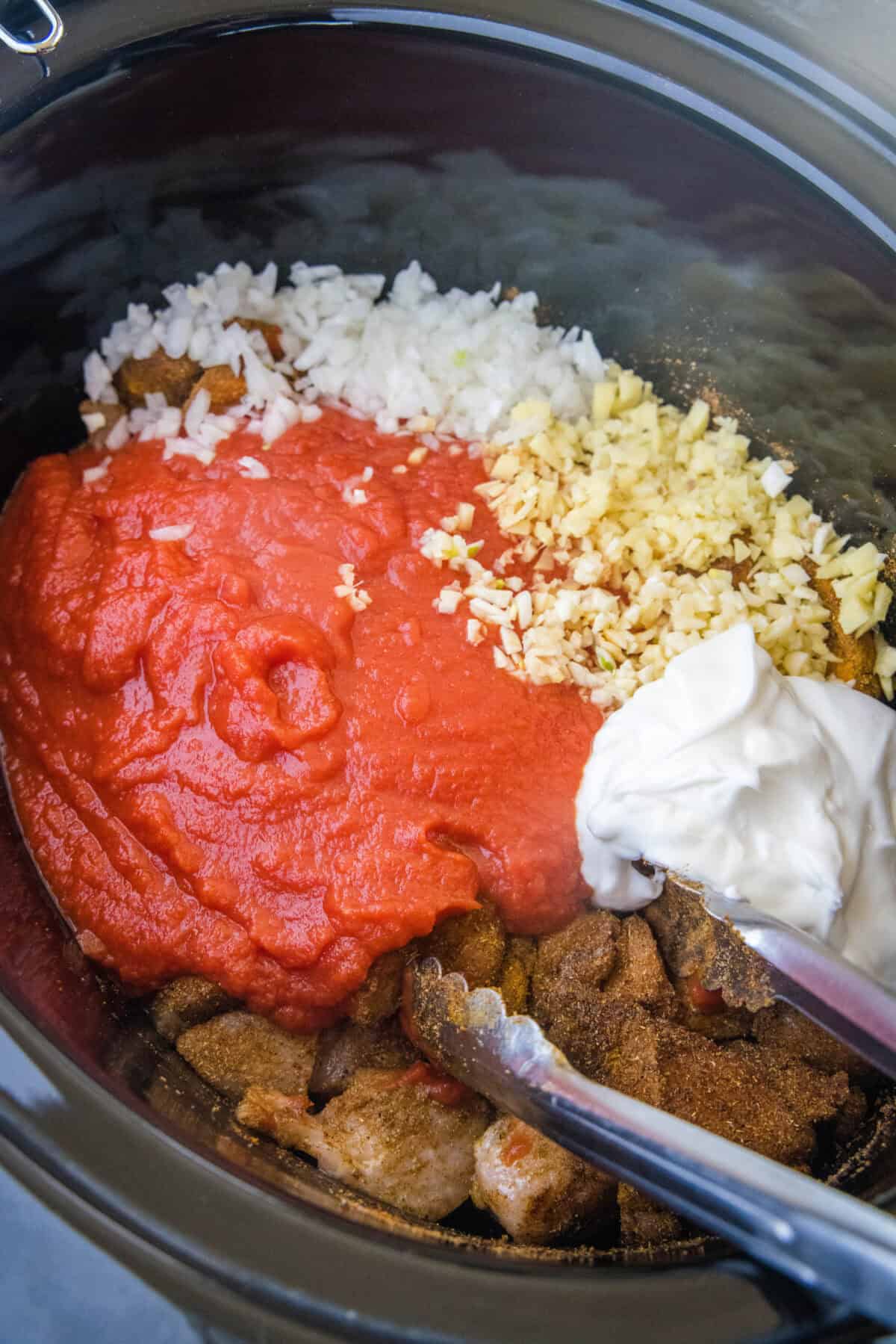 adding tomato puree, yogurt, garlic, ginger and onion to crockpot