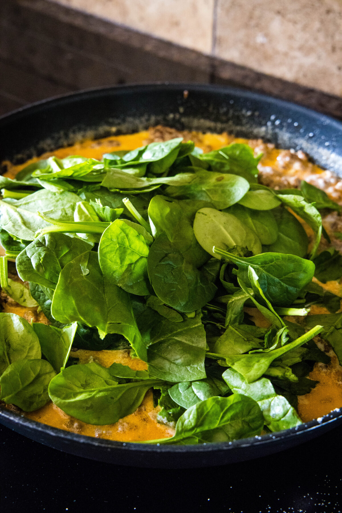 adding spinach to skillet with sauce