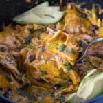 close up scooping chicken enchilada casserole from crockpot