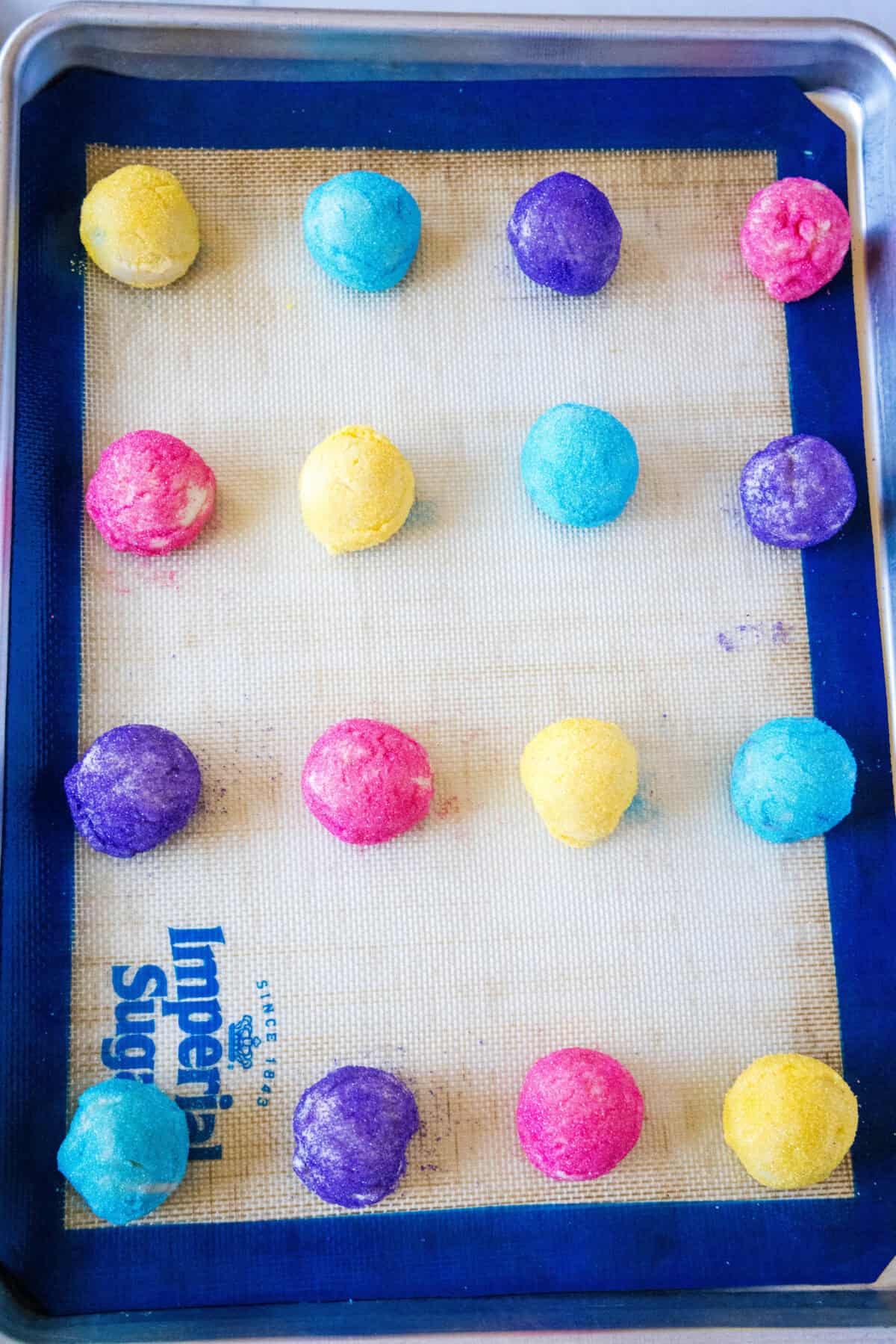 balls of sugar cookie dough rolled in sugar on baking tray