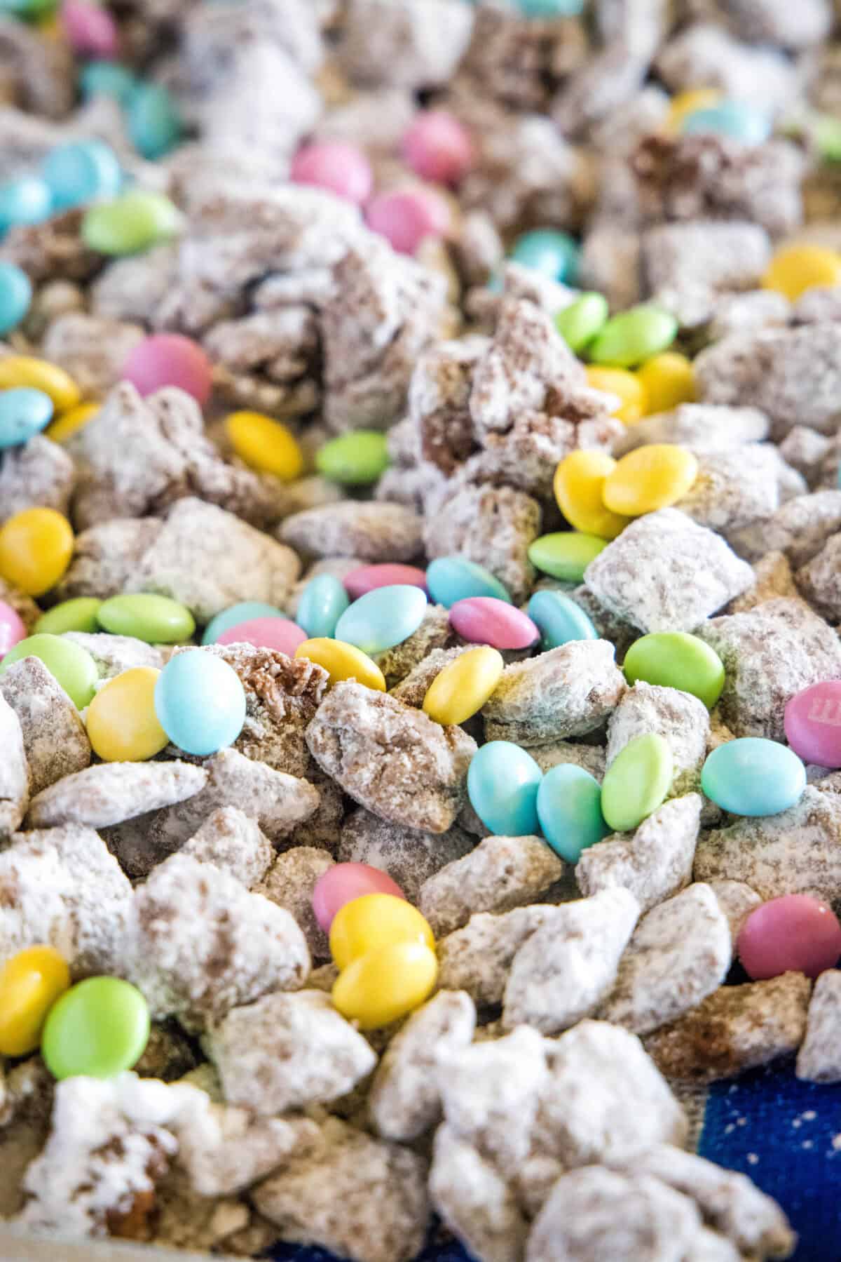 adding easter candy to the muddy buddies on a baking tray